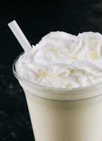 Glass with white milkshake and cream photo