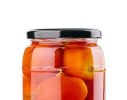 Pickled tomatoes in glass jar on white background photo