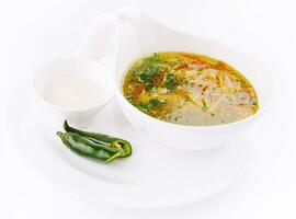 Chicken soup or broth with noodles, herbs and hot green pepper photo