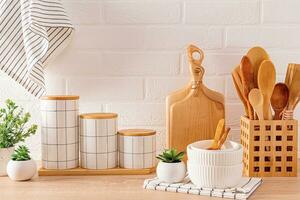 Beautiful kitchen background with set of cutting boards, wooden spoons, bowls, ceramic stylish storage jars. Front view. Eco-friendly kitchen . photo