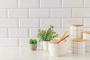 Beautiful kitchen background in white tones. A set of stylish ceramic jars for storing bulk products, bowls, potted indoor plants. Front view. photo