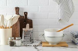 A set of various kitchen tools made of eco-friendly materials on a marble white countertop. Front view. A cozy, zero-waste home. photo