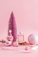 nuevo años composición con un botella de perfume y decoraciones para el día festivo. un rosado Navidad árbol, un trineo, un juguete pájaro. vertical ver foto