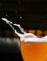 Glass of splashing beer close up photo