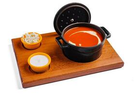 Tomato soup gazpacho in stewpan and suluguni cheese photo