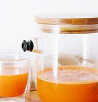 Hot drink from a sea-buckthorn in a glass cup and jug photo
