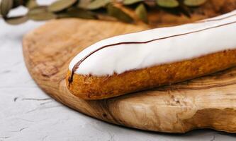 Glazed eclair dessert on wood closeup photo