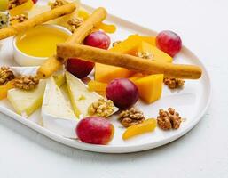 cheese platter with honey, nuts and red grapes photo