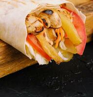 Rustic shawarma with french fries, mushrooms, chicken in pita bread photo