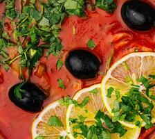 red soup Solyanka, with sausage, olives and lemon photo