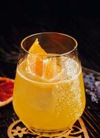 Glass of orange alcoholic drink with ice and slice of orange photo