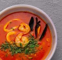 Tom yum soup with shrimp, squid and mussels top view photo