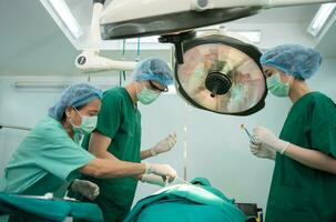 equipo de cirujanos profesionales asiáticos que realizan cirugía en el quirófano, cirujano, asistentes y enfermeras que realizan cirugía en un paciente, cáncer de atención médica y concepto de tratamiento de enfermedades foto