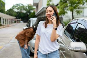 Asian women driver check for damage after a car accident before taking pictures and sending insurance. Online car accident insurance claim after submitting photos and evidence to an insurance company.