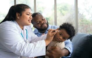 Pediatric doctor examining ear for a hearing test examining cute little girl in medical healthcare hospital or clinic. Smiling African American Baby whit pediatrician in hospital photo