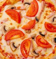 Pizza with ham, tomatoes and mushrooms on top view photo