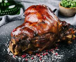 Roast pork knuckle on black plate photo