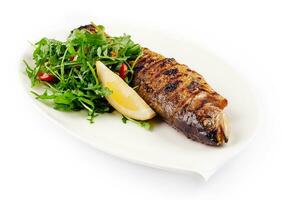 Grilled sea bream fish, lemon, arugula on white plate photo