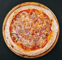 Pizza with tuna and red onion on wooden cutting board photo