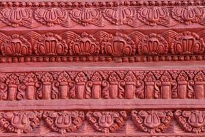 The concrete walls are painted in red and have simple carved patterns. photo