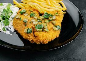 Delicious wiener hunter schnitzel with sauce and french fries close-up on a plate photo