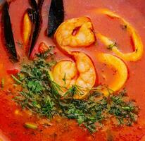 Tom yum soup with shrimp, squid and mussels top view photo