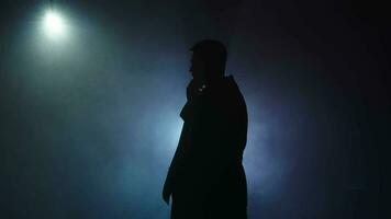 silhouette, irriconoscibile uomo artista nel un' fumoso camera con sostegno blu neon luce. palcoscenico leggero a un' concerto mostrare. lento movimento. video