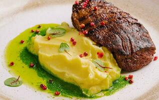 Mashed potatoes and beef steak with pesto sauce photo