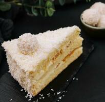 Coconut layered, raffaello cake on black tray photo