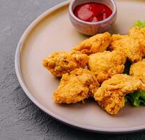 Delicious crispy fried chicken breast strips with tomato sauce photo