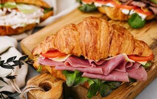 Delicious croissant sandwich on wooden board photo