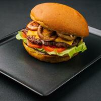 Burger with mushrooms and cutlet on black tray photo