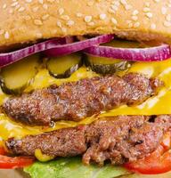Double patty burger with pickles close up photo