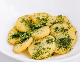 Fried potato slices with dill on a white plate photo