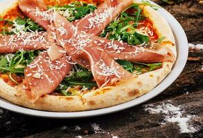 delicious Italian pizza with prosciutto and arugula photo