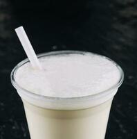 milkshake in a plastic cup on black background photo