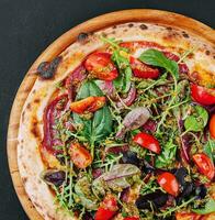 Top view pizza with salami, tomatoes and basil with arugula photo