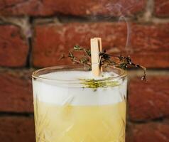 Delicious light yellow sour foam cocktail in the etched glass photo