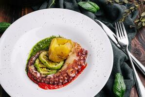 Grilled Sicilian octopus with sliced zucchini, potatoes, and pesto sauce photo