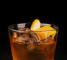 Old-fashioned cocktail with ice and orange peel photo