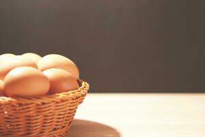 The eggs in the brown wicker basket on the table. photo