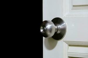 Stainless steel door knob or the handle on the wooden door In a brightly lit room. Darkroom background. concept of cleanliness and hygiene. Selective focus. photo