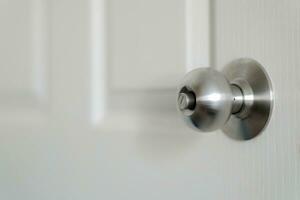 Stainless steel door knob or the handle on the wooden door In a brightly lit room. concept of cleanliness and hygiene. Selective focus. photo