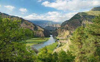hermosa paisaje con montañas, Valle y un río en un soleado verano día con nubes daguestán foto
