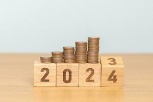 flipping 2023 to 2024 year block with Coins stack. Money, Budget, tax, investment, financial, savings and New Year Resolution concepts photo