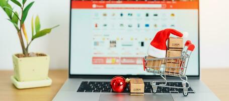 Christmas Online Shopping concept. Boxes with shopping cart on a laptop computer. Sale and discount during Christmas and New Year holiday, ecommerce, shipping delivery, logistics and Cyber Monday photo