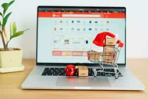 Christmas Online Shopping concept. Boxes with shopping cart on a laptop computer. Sale and discount during Christmas and New Year holiday, ecommerce, shipping delivery, logistics and Cyber Monday photo