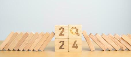 2024 year and falling blocks with magnifying glass icon. SEO, Search Engine Optimization, hiring , Advertising, Risk Management, recession, goal, New Year planning and inflation economy concepts photo