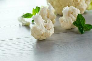 slices of raw small raw cauliflower on wooden table photo