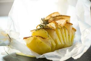 Baked potatoes stuffed with lard in baking paper. photo